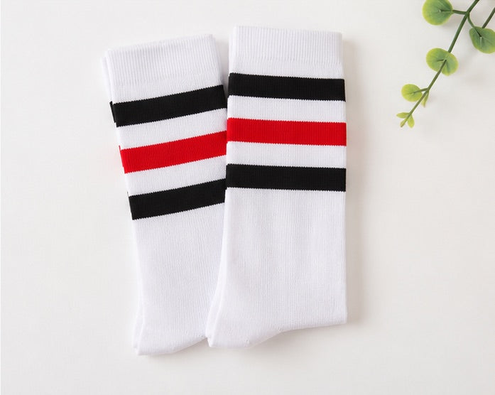 Flat lay of a pair of LIUMI Kids striped knee-high school socks in white with red and black striped cuffs